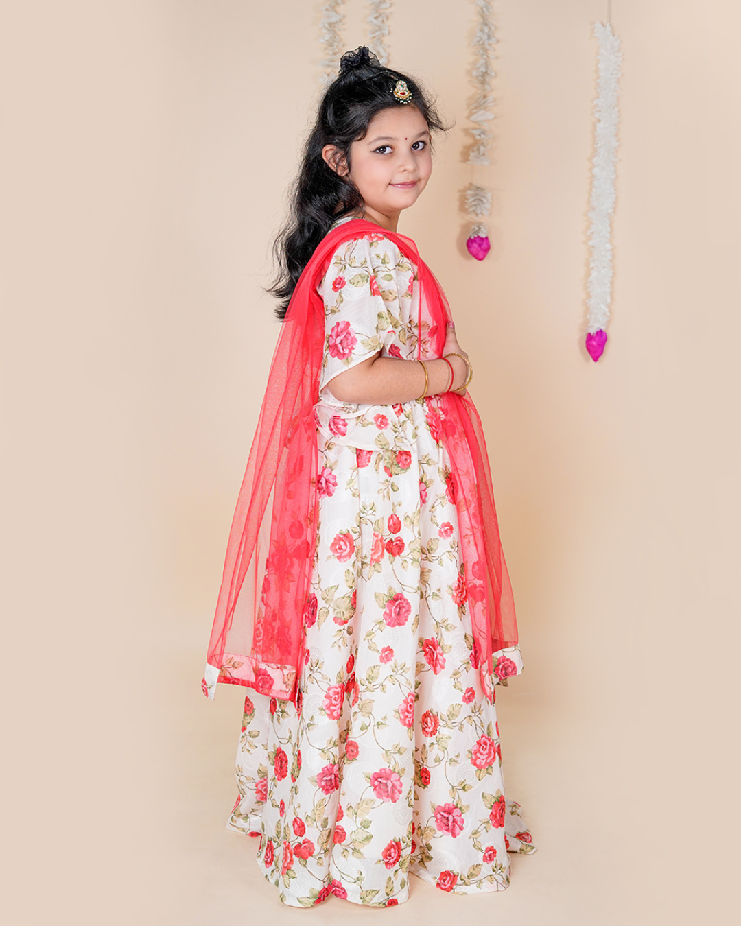 Young girl in a floral dress with a pink dupatta against a beige background