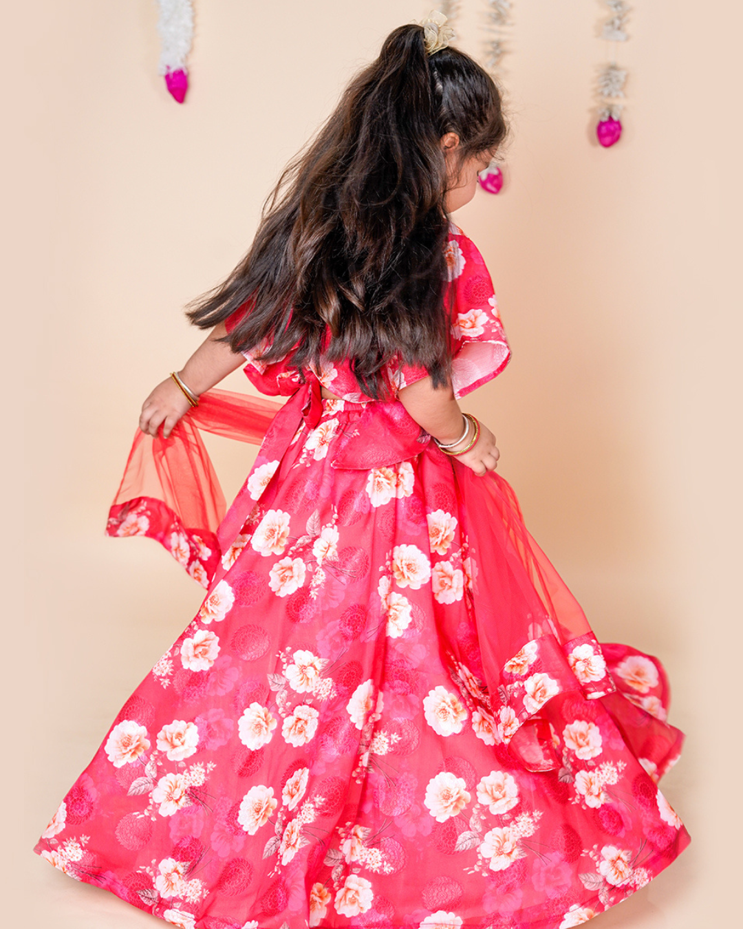Young girl wearing a red floral dress against a beige background