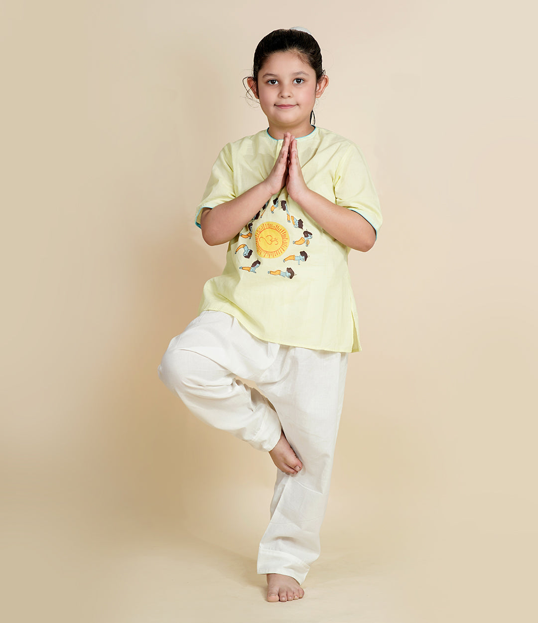Child wearing Chanda Mama pista green Krishna yoga outfit with Surya Namaskar print and white cotton pants