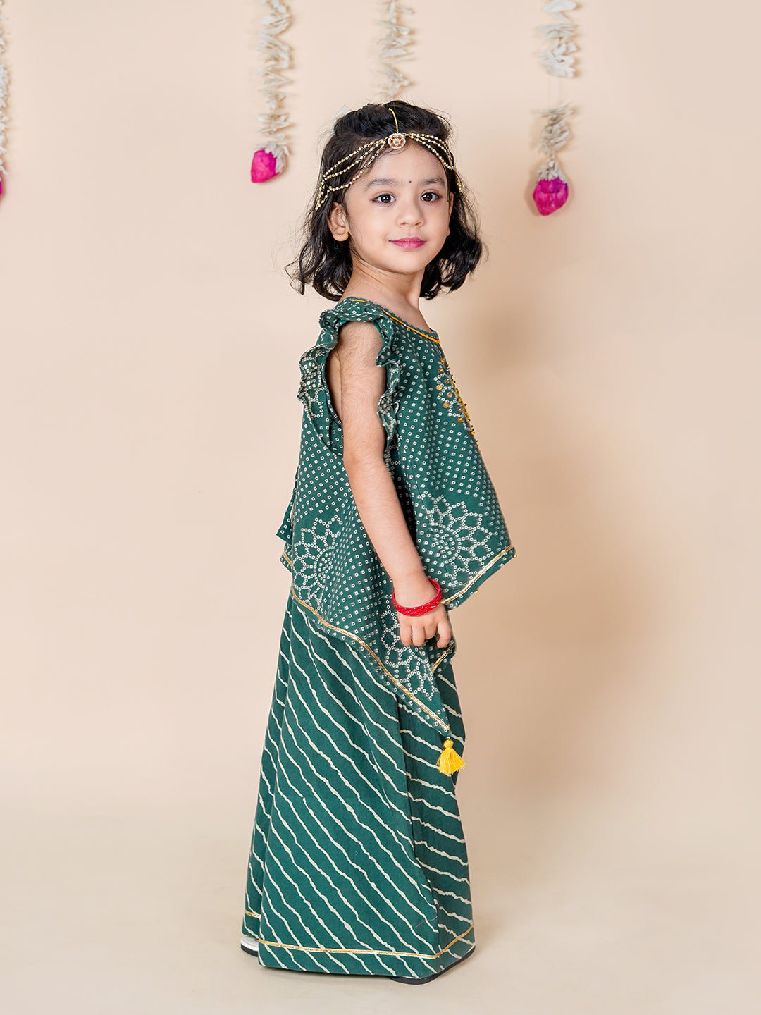 Young girl in a green traditional outfit with a beige background