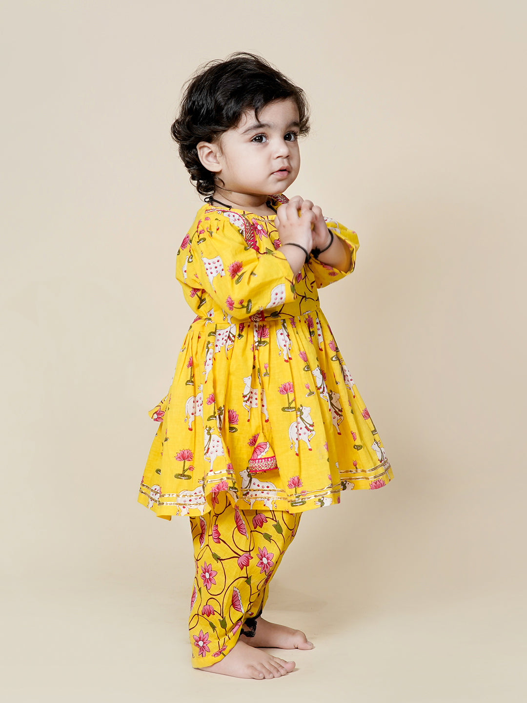 Child wearing a yellow floral outfit on a beige background