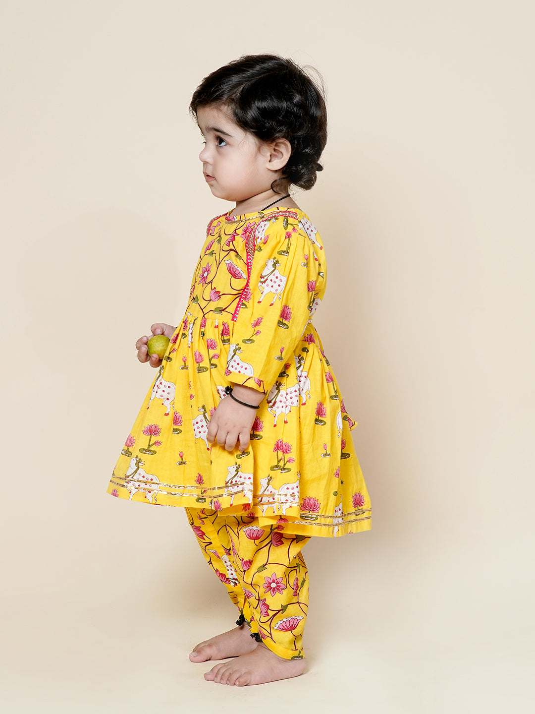 Child wearing a yellow floral outfit on a beige background