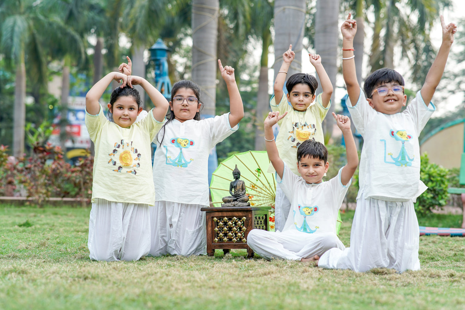 Group of kids practicing yoga wearing Chanda Mama kids yoga outfits – white cotton set with meditating monkey print and pista green set with Little Krishna Surya Namaskar block print.