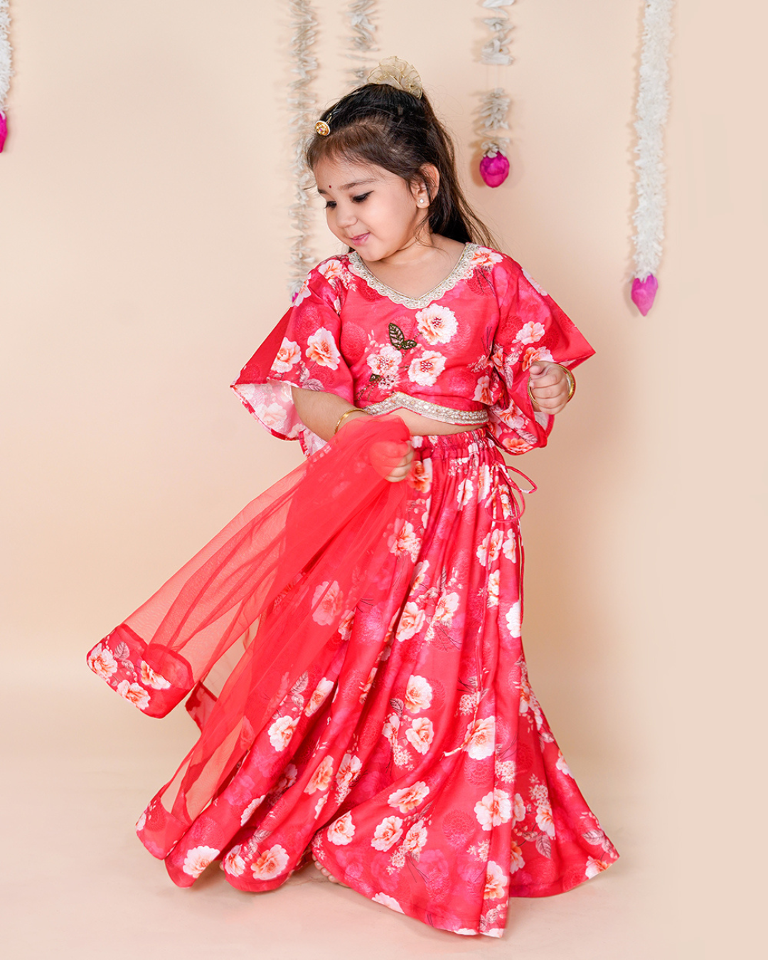 Young girl in a red floral dress standing against a beige background