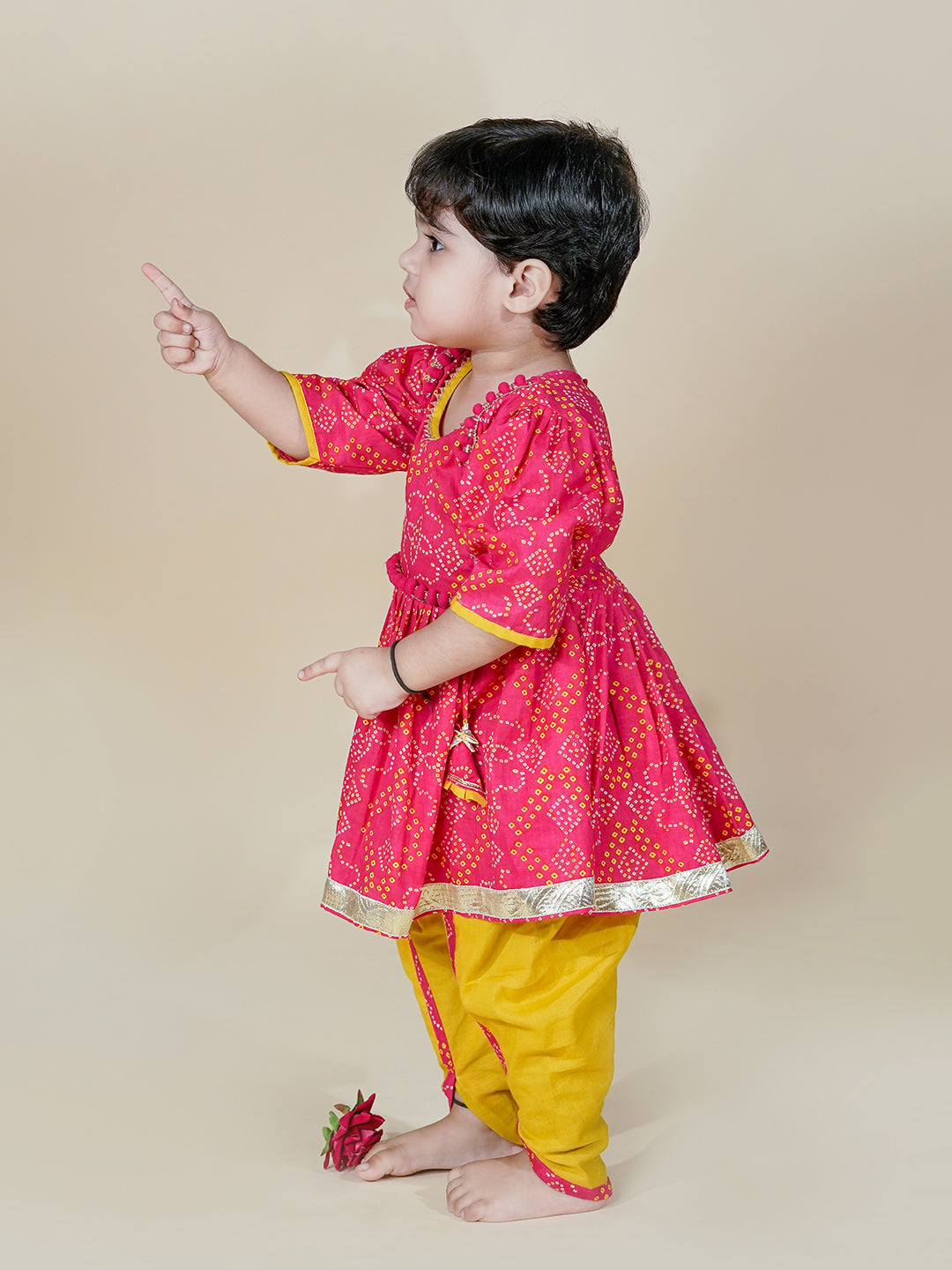 Child wearing a pink and yellow traditional outfit on a beige background
