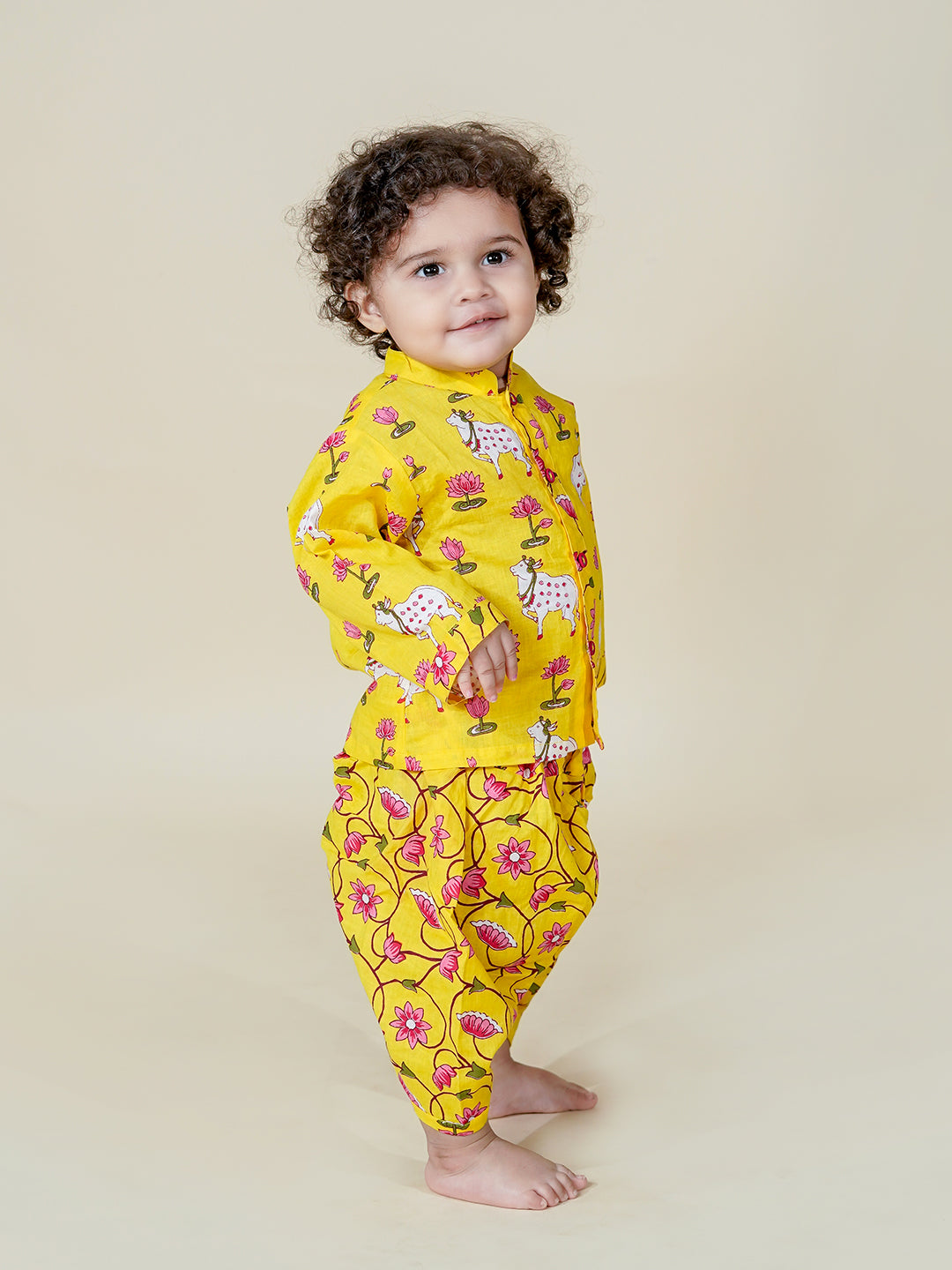 Child wearing a yellow floral onesie on a beige background