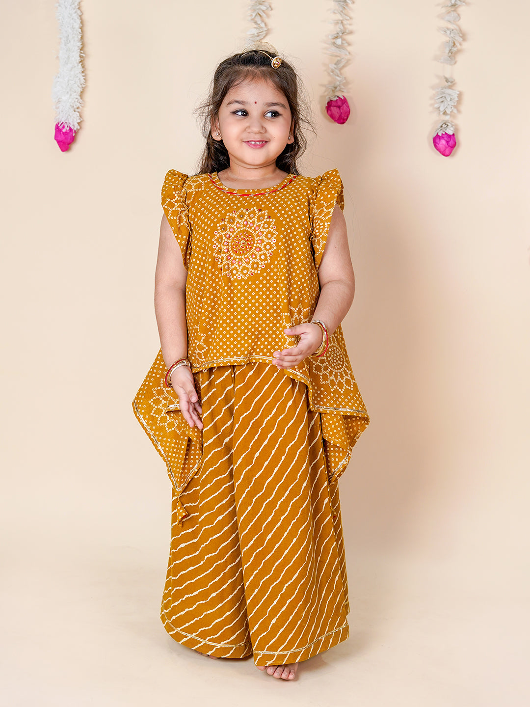 Young girl wearing a mustard yellow traditional outfit with a floral design on a beige background