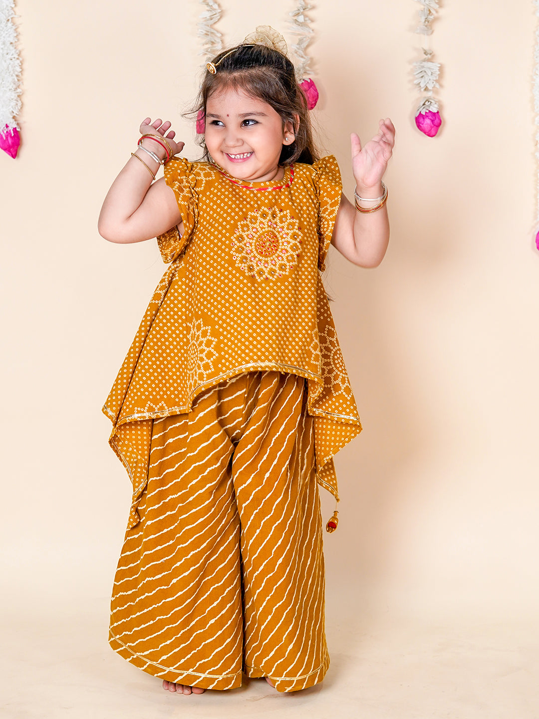 Child wearing a mustard yellow traditional outfit with floral patterns on a beige background